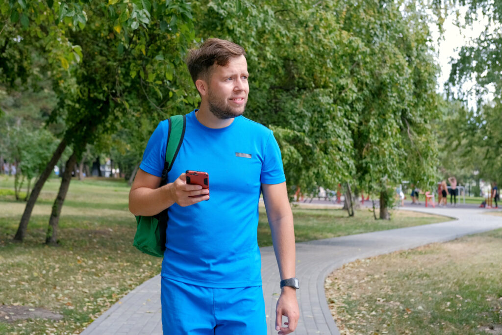 Мужчина гуляет в парке с телефоном