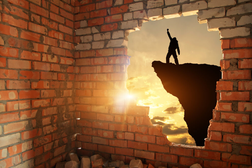 Силуэт человека на скале через проломленную стену
