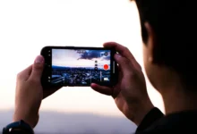Человек держит смартфон вертикально и смотрит короткое видео в ленте соцсети, на экране абстрактная карточка товара без логотипов, мягкий домашний фон
