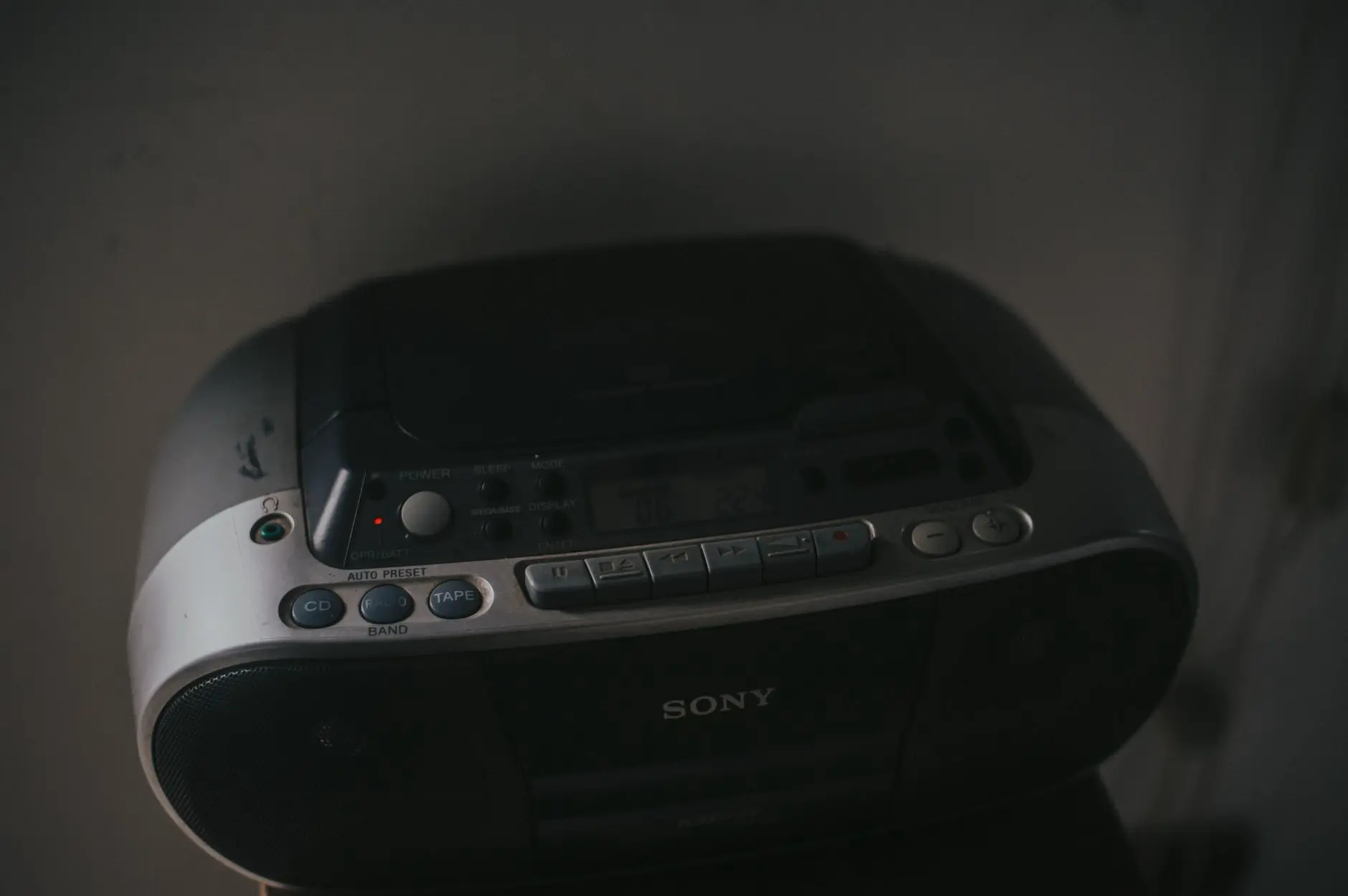 Молодой человек слушает музыку через портативный CD-плеер в парке