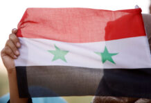 США и Сирия: диалог о смягчении санкций и восстановлении страны A woman holds a Syrian flag in Deraa