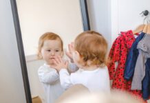 малыш смотрит на себя в зеркале