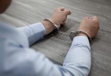 Новый закон о персональных данных: как защитить специалистов по информационной безопасности и обеспечить эффективную киберзащиту Selective focus shot of male hands in handcuffs on a wooden table