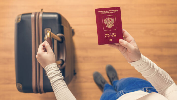 Top view of a girl with a suitcase and a Russian passport walking on the airport to passport control