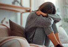 Психолог Лысакова объяснила влияние социальных норм на женское счастье DepressedYoungWomanSittingOnCouchInTheLivingRoom