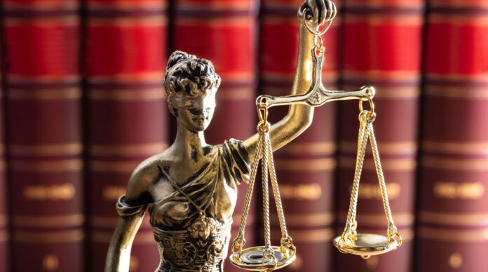 Justice Statue In Front Of Red Law Books
