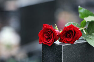 Red,Roses,On,Black,Granite,Tombstone,Outdoors,,Space,For,Text.