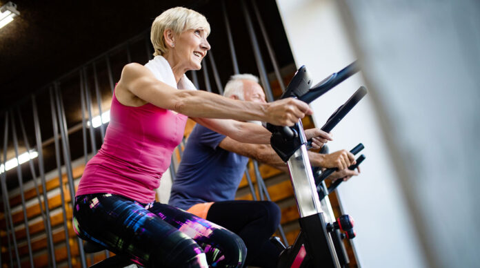 Happy senior people doing indoor biking in a fitness club