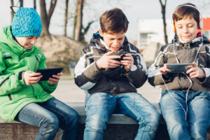 Three boys using mobile phones in the park