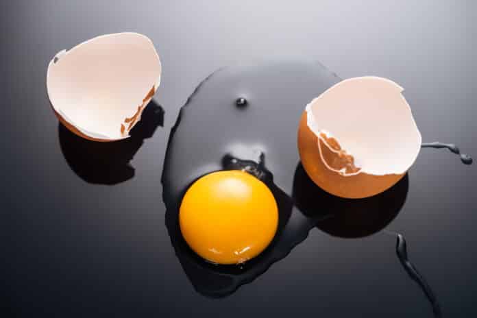 close up of fresh smashed egg with yolk, protein and eggshell on black background разбитое яйцо с желтком, белком и яичной скорлупой
