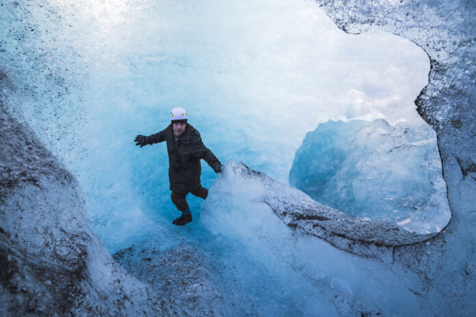 Tourist exploring an ice cave on adventure vacation at Breidamerkurjokull Glacier, Vatnajokull Ice C турист гуляет среди льдов