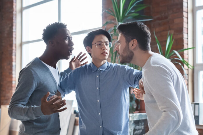 Young angry coworkers having quarrel at office два молодых мужчины спорят
