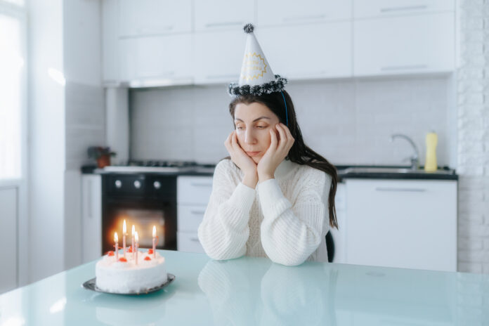 Lonely woman celebrating her birthday with a cake at home in her kitchen. одинокий день рождения