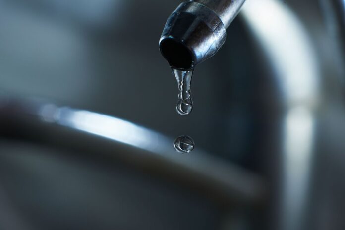 Reverse osmosis filter tap closeup with dripping water-drop. Вода льётся из-под крана