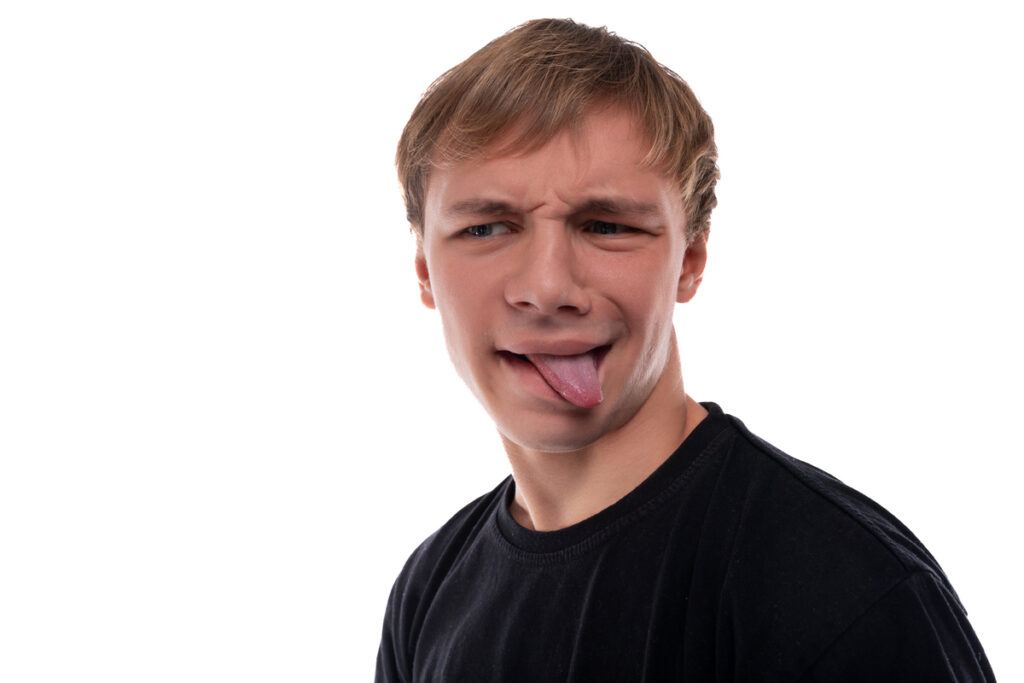 Белокурый подросток показывает язык