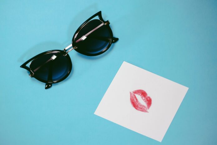 Emotional faces: black sunglasses and colourful print of lipstick on paper Черные солнцезащитные очки и след от помады на бумаге