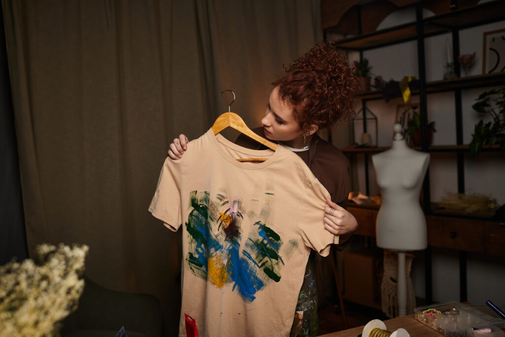 Девушка держит в руках футболку