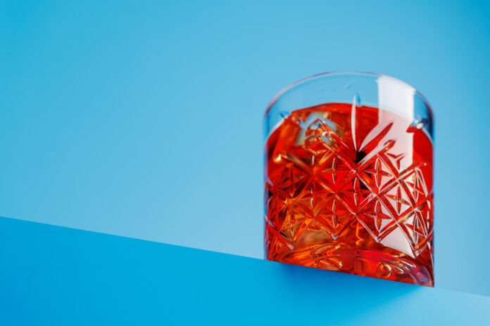 Classic negroni against a cool blue background Красный напиток на столе