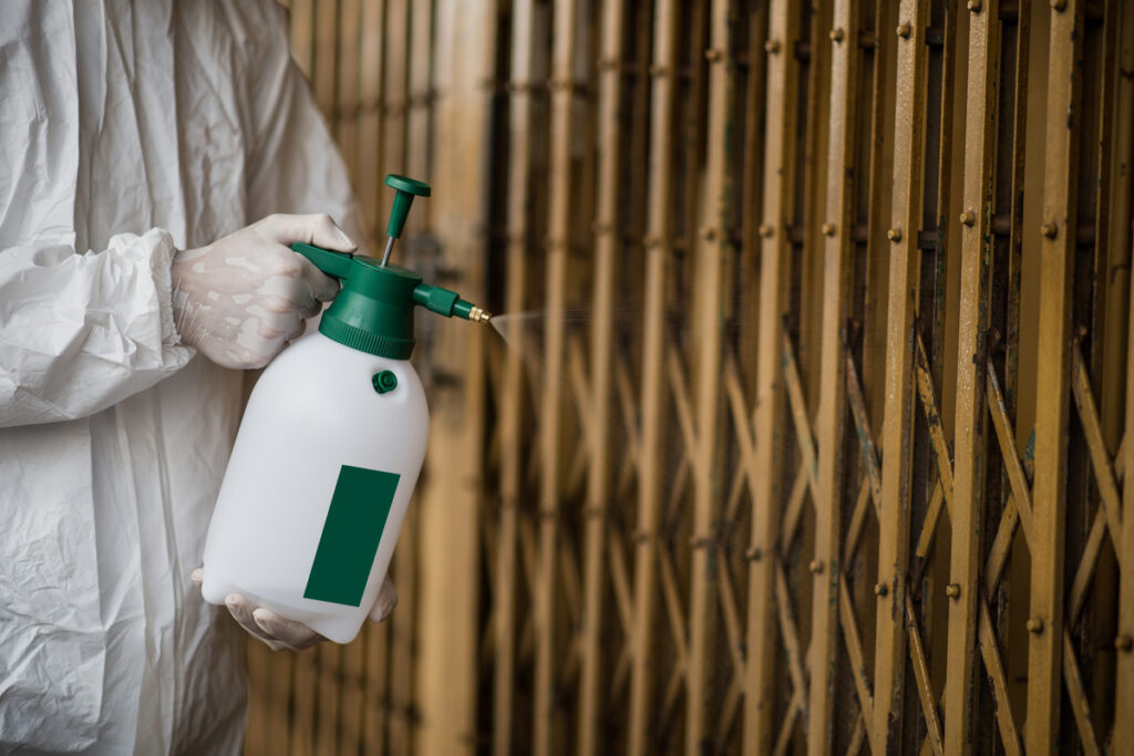 Мужчина в защитном костюме распыляет пестициды