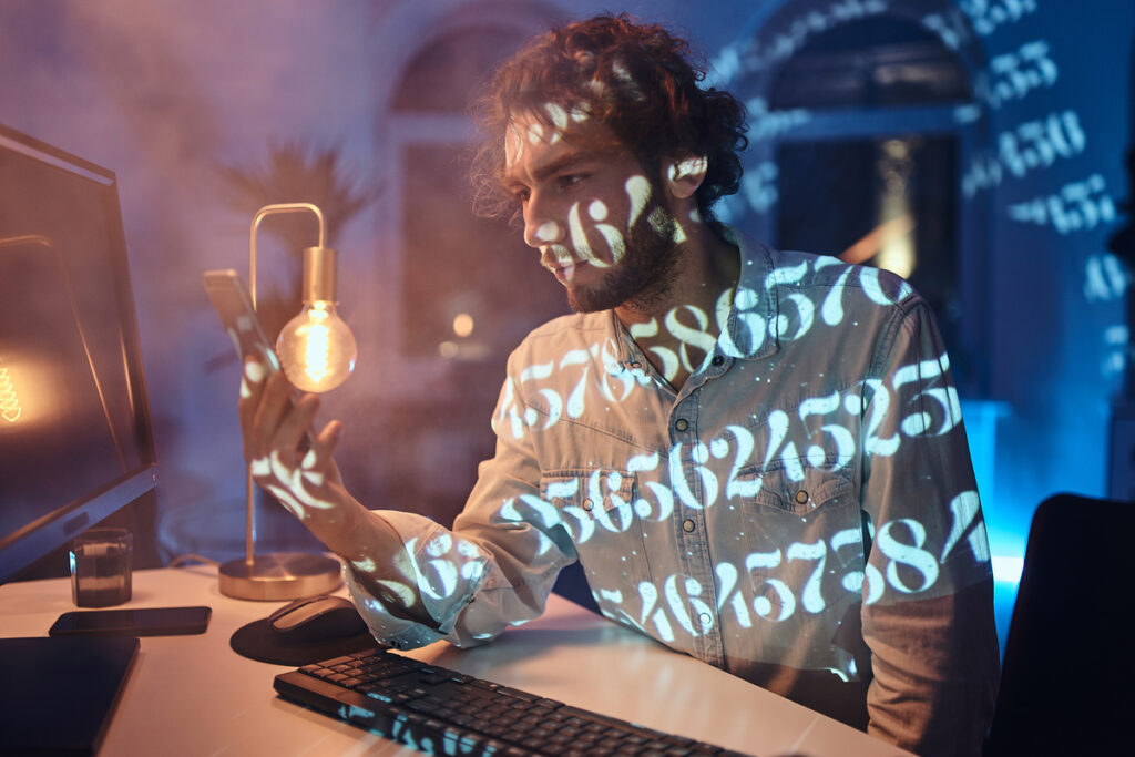 Парень сидит за столом и смотрит на телефон