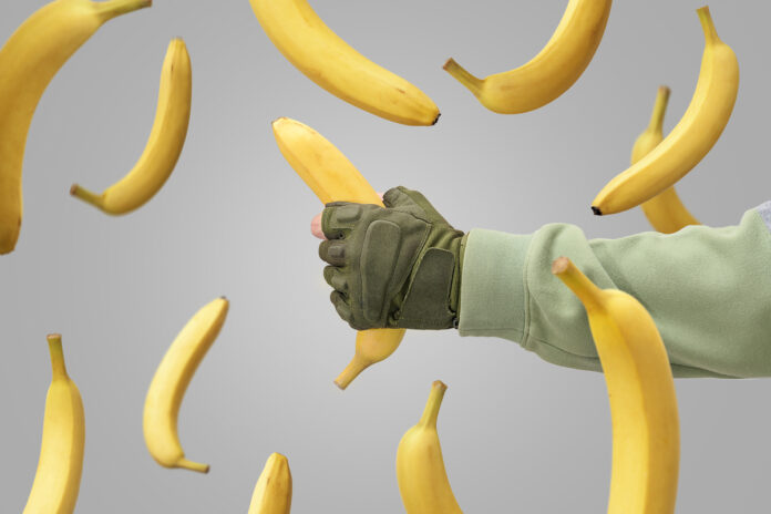 A man's hand caught a falling banana. Falling bananas against a Рука мужчины поймала падающий банан