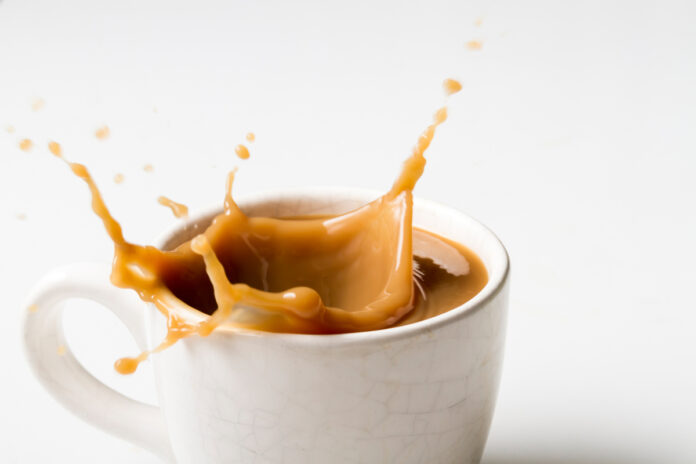 Cup of splashing coffee on white background Брызги кофе в чашке