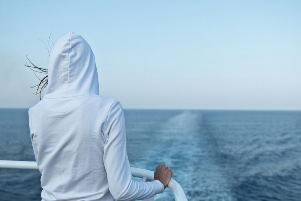 Молодая женщина смотрит на океан с лайнера