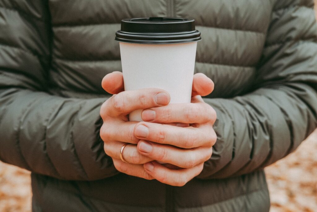 Мужские руки держат бумажный стаканчик с кофе