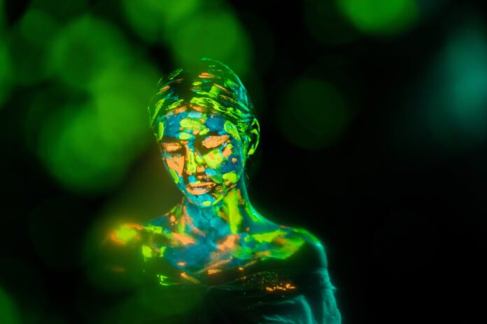 portrait of woman painted with bright neon paints on black backdrop with bokeh lights Портрет женщины, нарисованный неоновыми красками