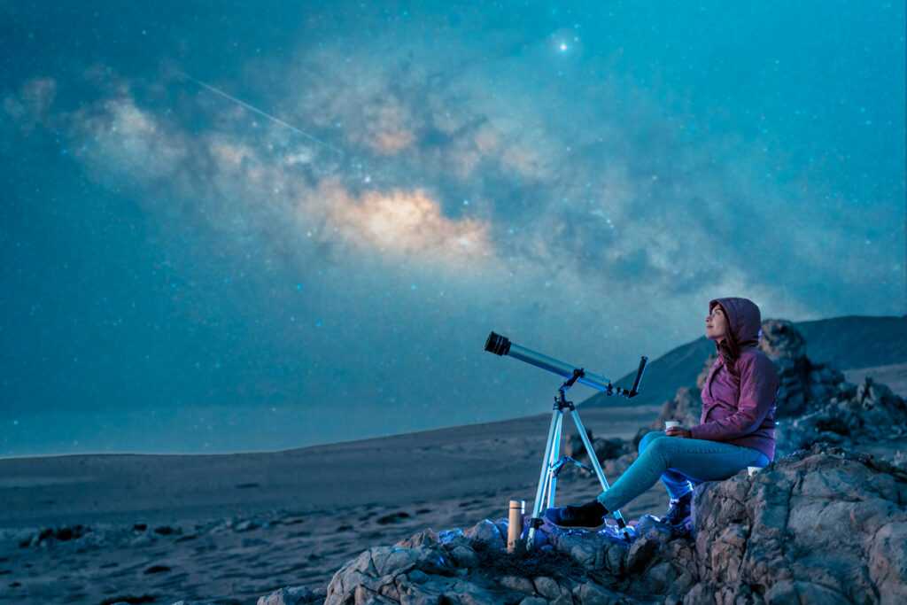 Женщина сидит в пустыне одна, созерцая звездное небо