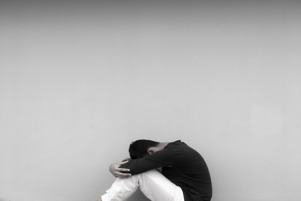 Депрессивный парень, сидящий у стены