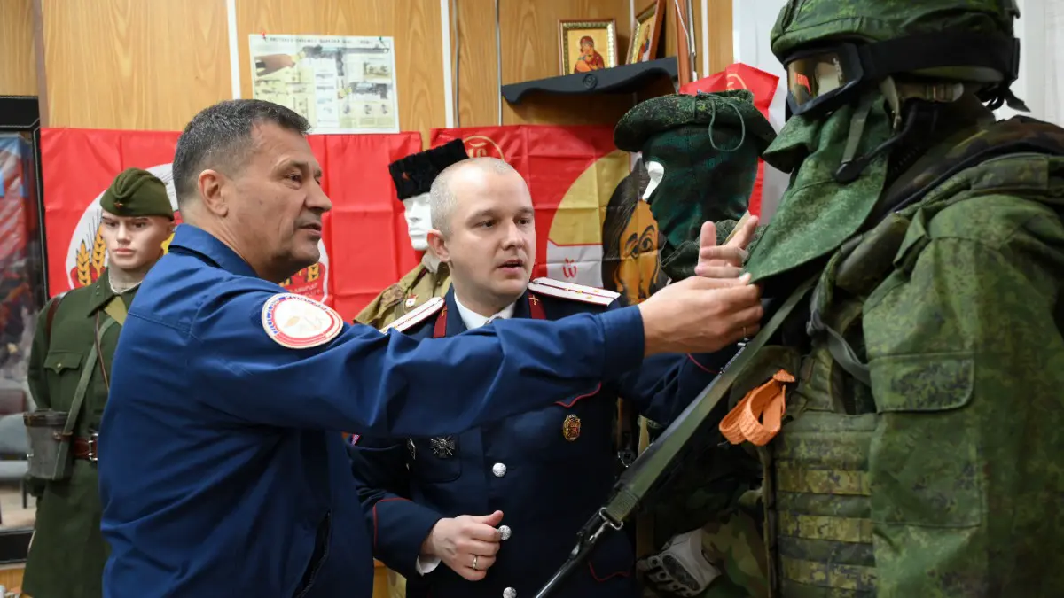 Директор Тушинской автошколы ДОСААФ России Владислав Кириллов и атаман Хуторского казачьего общества «Южное Тушино» Сергей Семенов показывают форму бойца СВО 2024–2025 годов, которая стала частью экспозиции выставки «Казачество на службе Государства Российского сквозь века»