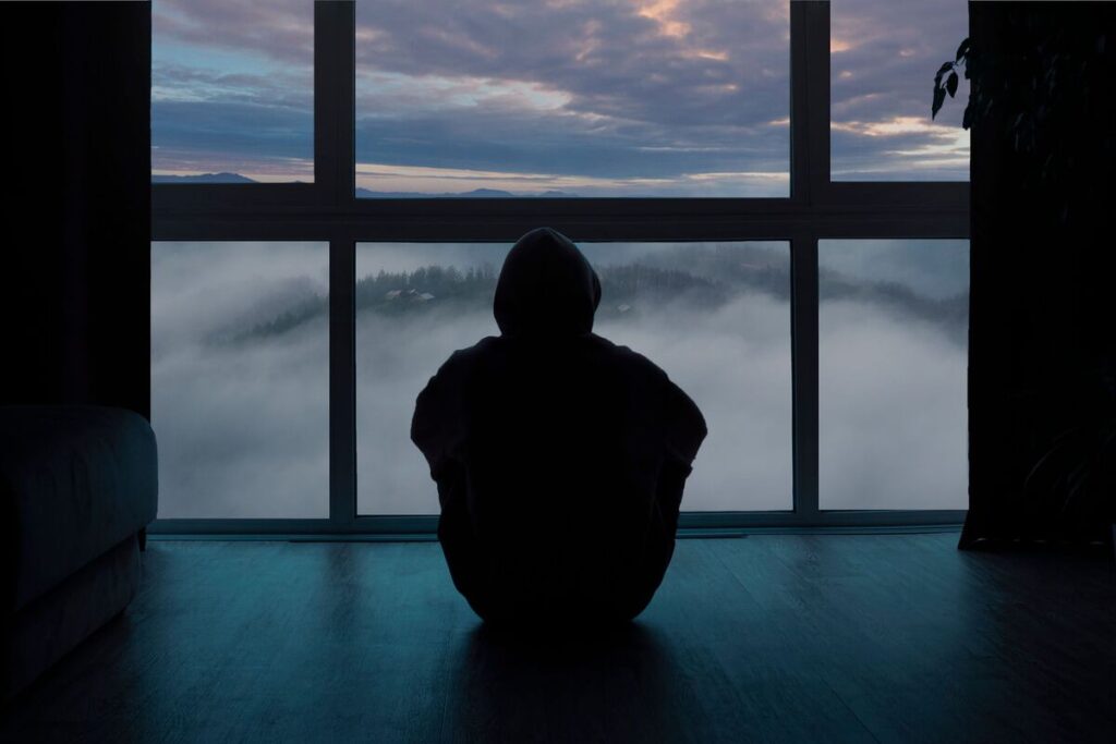 одинокий человек сзади сидит у окна 
