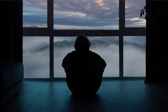 одинокий человек сзади сидит у окна