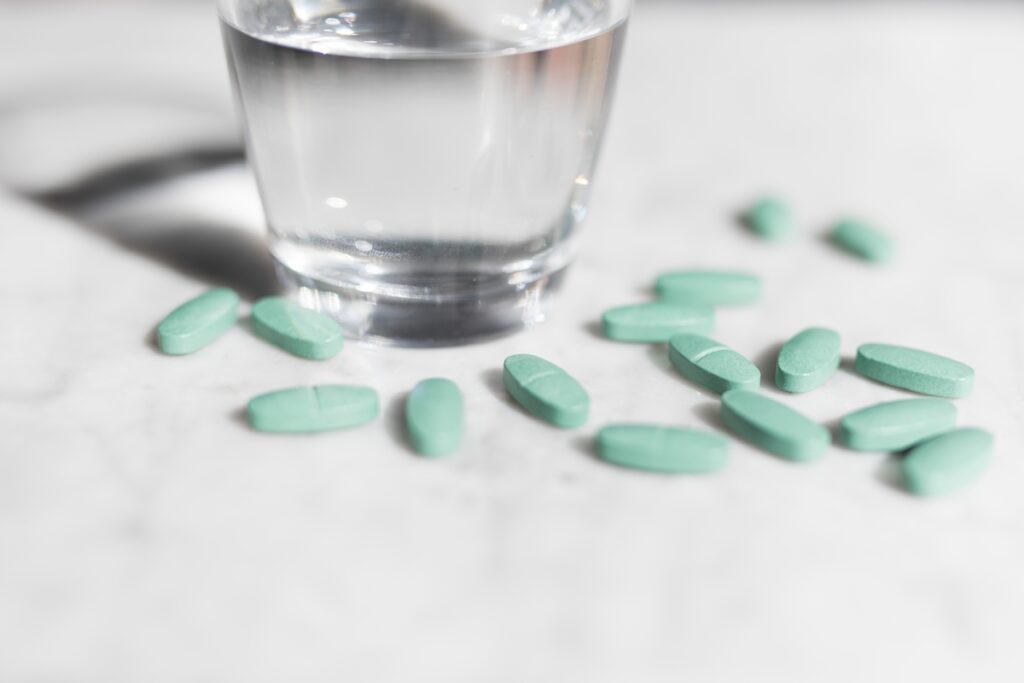 Белые таблетки и стакан воды