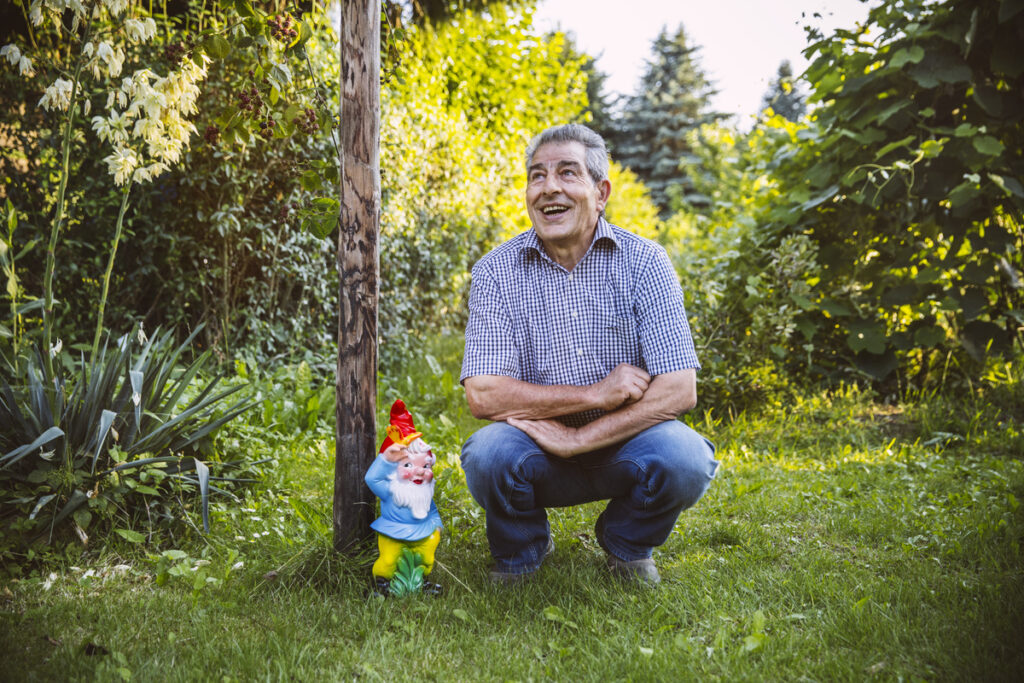 пожилой человек сидит у садового гнома