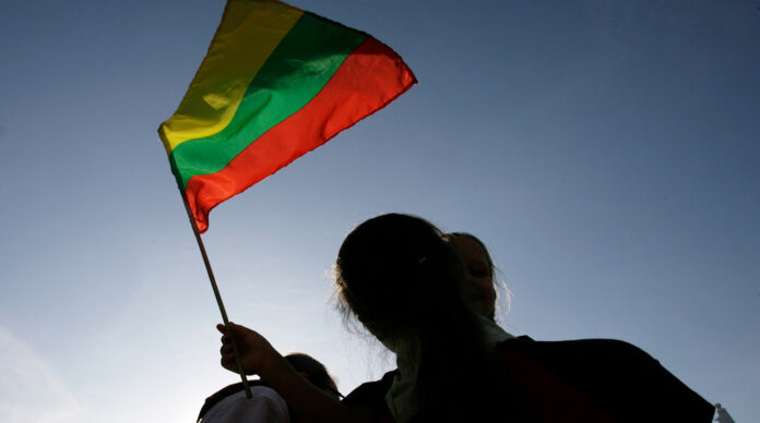 A girl holds Lithuanias flag as she watches the start of the Baltic Run event in Vilnius