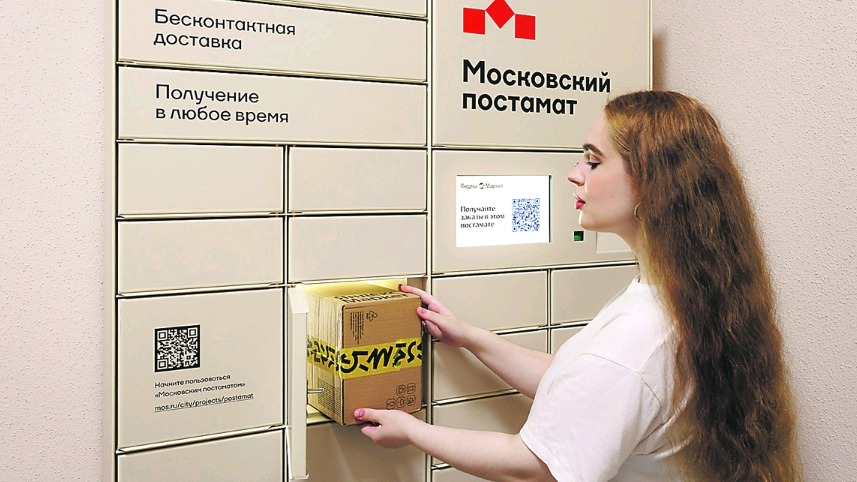 Жительница столицы забирает посылку из постамата в своем подъезде 