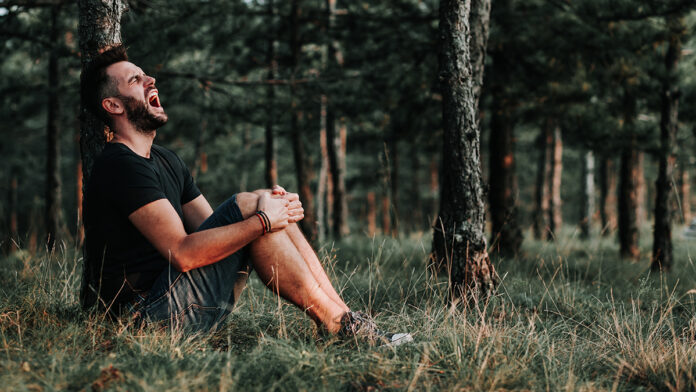 YoungDepressedManSittingAloneInTheForest