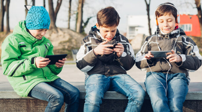 Three boys using mobile phones in the park