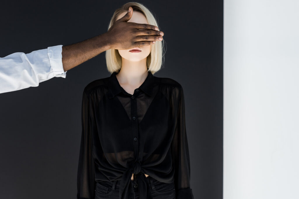 Мужчина закрывает глаза девушке