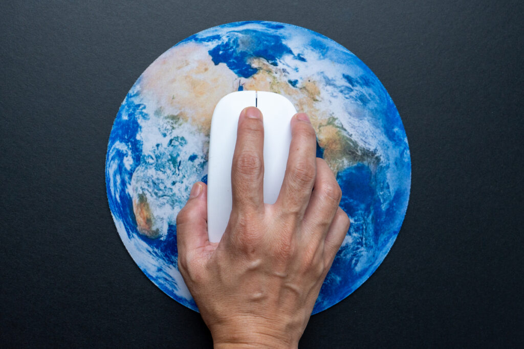 Рука, управляющая компьютерной мышью на земном шаре