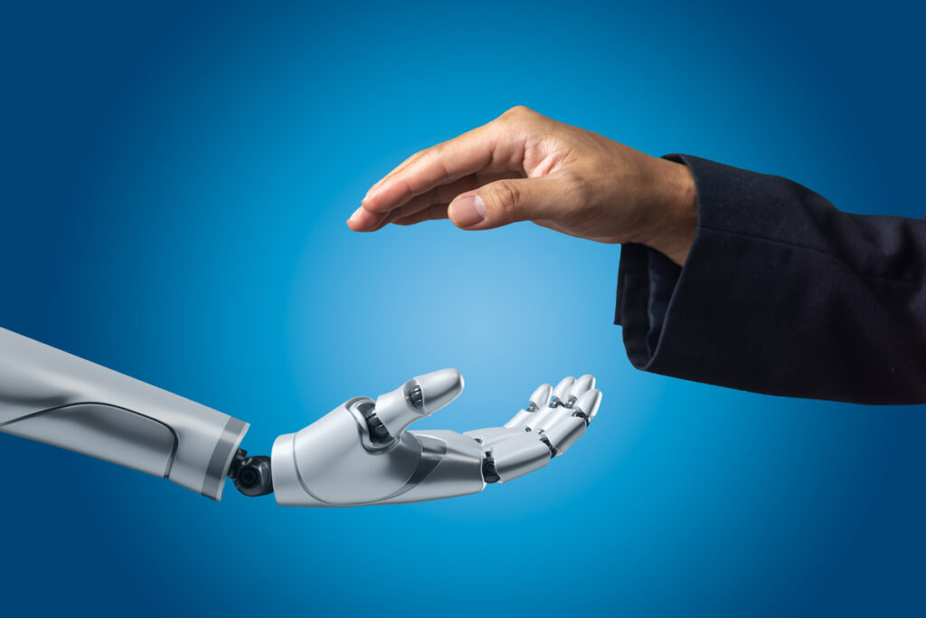 Рука робота готовится пожать человеческую руку