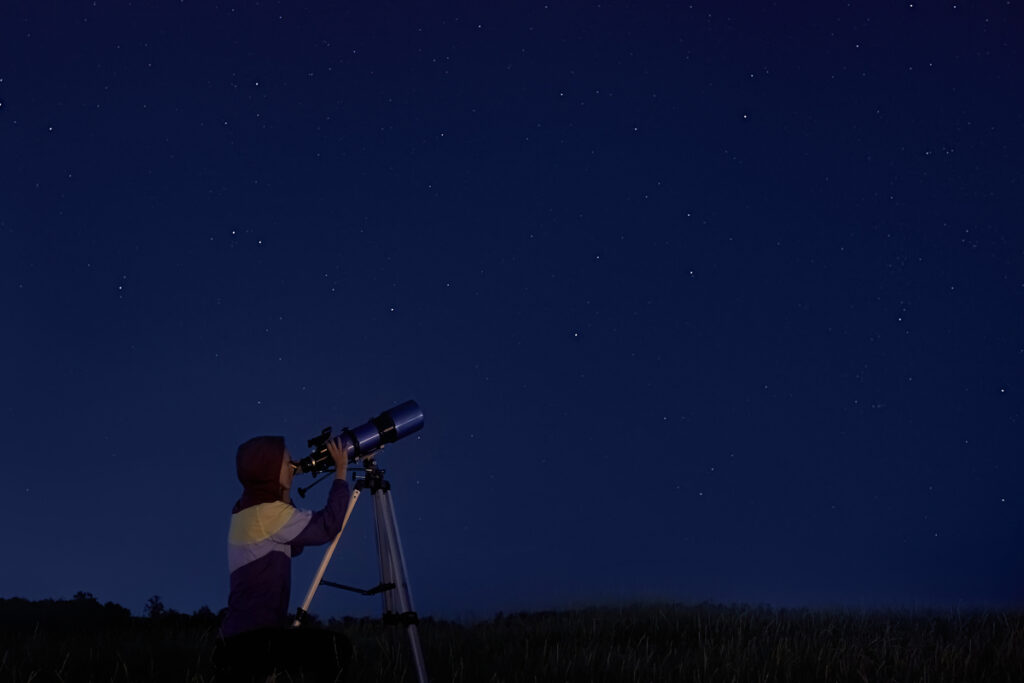 Женщина смотрит в оптический телескоп