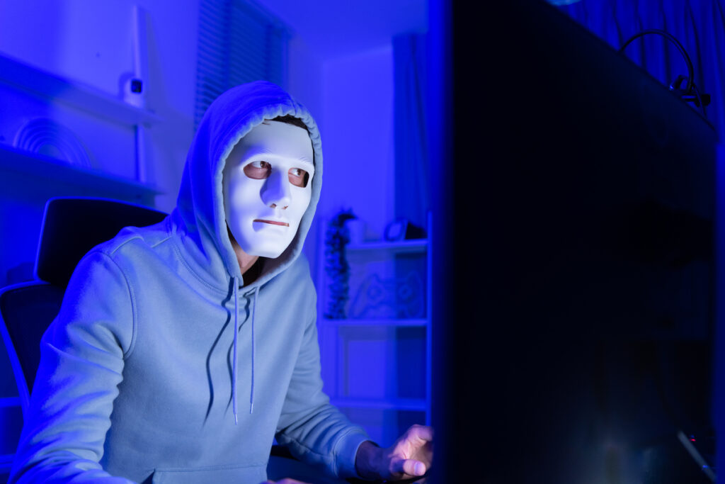 Мужчина в маске сидит перед компьютером
