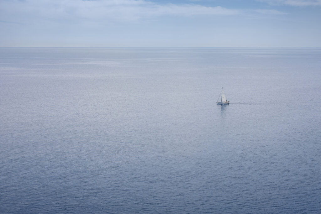 Океан и дрейфующая яхта на горизонте
