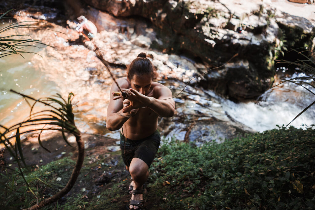 Парень с обнаженной грудью в шортах и сандалиях поднимается по склону