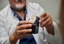 Недавние медицинские прорывы, которые вдохновляют Врач-мужчина демонстрирует пациенту слуховой аппарат