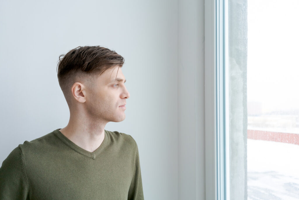 Мужчина смотрит в окно