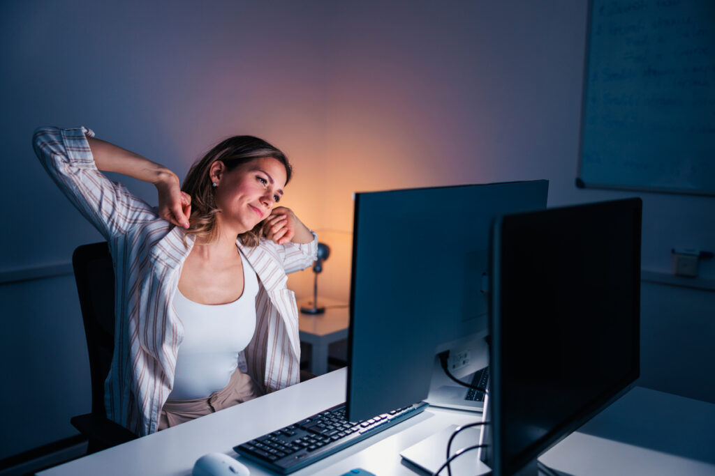 Женщина, потягивающаяся за столом